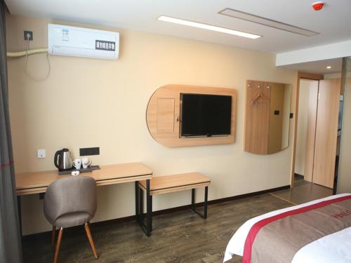um quarto de hotel com uma secretária e uma televisão na parede em Thank Inn Chain Hotel Jiangsu Yancheng Funing County Jinsha Lake em Yancheng