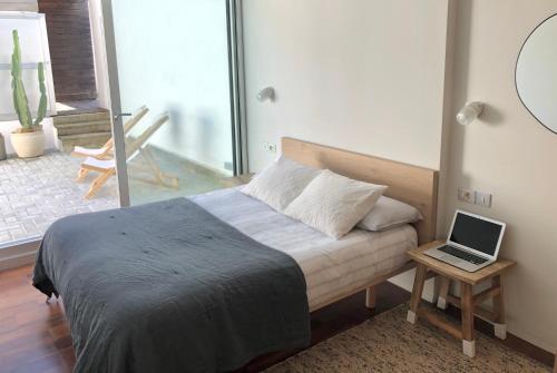 1 dormitorio con cama y mesa con ordenador portátil en Morada Do Pablinho en Isla de Arosa
