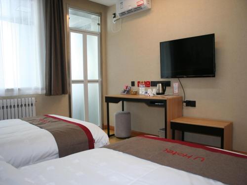 a hotel room with two beds and a desk with a television at Thank Inn Chain Hotel shandong dezhou development zone dongzi cultural park in Dezhou