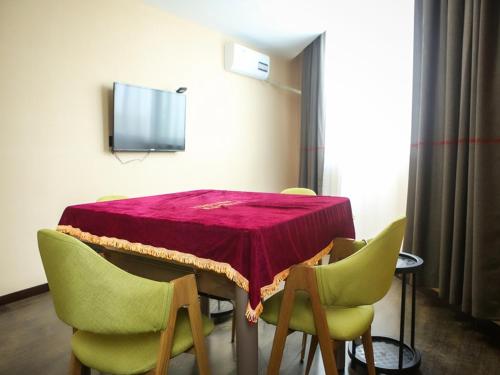 uma mesa com cadeiras verdes e uma toalha de mesa vermelha em Thank Inn Chain Hotel Jiangsu Yancheng Funing County Jinsha Lake em Yancheng