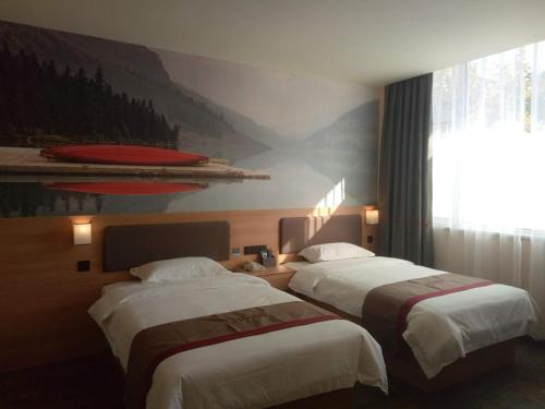 two beds in a hotel room with a painting on the wall at Thank Inn Chain Hotel shandong binzhou bincheng district binbei in Binzhou