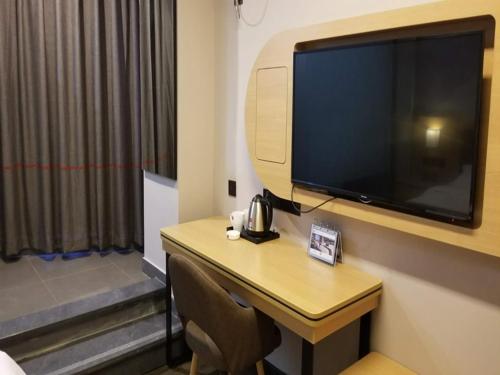 a room with a desk with a large television on a wall at Thank Inn Chain Hotel jiangxi ganzhou zhanggong district civilization avenue in Ganzhou