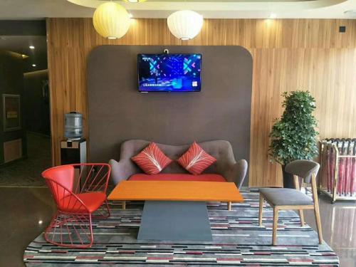 a living room with a couch and a tv on a wall at Thank Inn Chain Hotel shandong binzhou bincheng district binbei in Binzhou