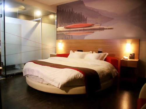 a bedroom with a large bed with a painting on the wall at Thank Inn Chain Hotel Fujian Quanzhou Anxi County Yongan Road in Quanzhou