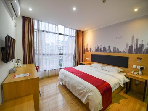1 dormitorio con cama, escritorio y ventana grande en Thank Inn Chain Hotel guangdong shenzhen airport hourui metro station, en Shenzhen