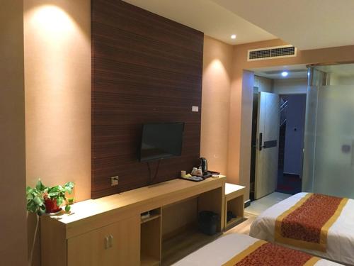 1 dormitorio con escritorio y TV en la pared en Thank Inn Chain Hotel sichuan ganzi luding county kangba bridge, en Lutingkiao