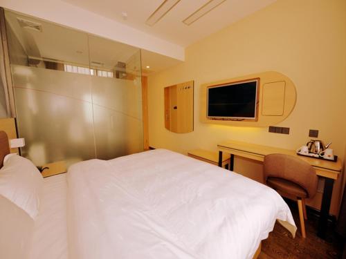 Habitación de hotel con cama y escritorio con TV. en Thank Inn Chain Hotel sichuan ziyang yanjiang district walmart en Ziyang