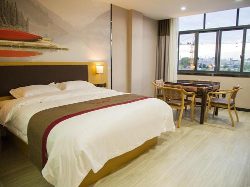 ein Hotelzimmer mit einem Bett, einem Tisch und einem Schreibtisch in der Unterkunft Thank Inn Plus Hotel jingxi shangrao economic development zone jingke avenue in Shangrao