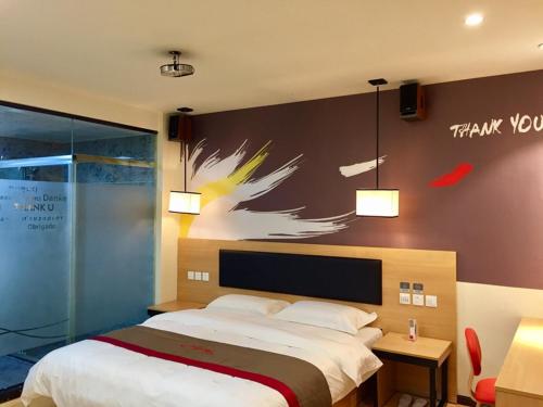 泉州市にあるThank Inn Chain Hotel fujian quanzhou fengze district donghai streetのベッドルーム1室(ベッド1台付)が備わります。壁には絵画が飾られています。