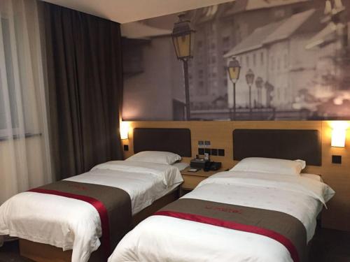 three beds in a hotel room with a painting on the wall at Thank Inn Chain Hotel guizhou zunyi chishui city red army avenue jinshui bay in Chishui