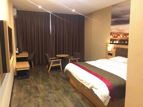 a hotel room with a bed and a table and chairs at Thank Inn Chain Hotel guangxi liuzhou luzhai county square in Liuzhou