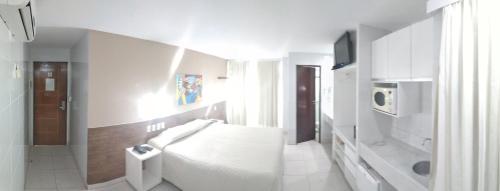 a white bathroom with a toilet and a sink at Hotel Corais de Tambau in João Pessoa