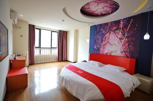a bedroom with a large bed and a painting on the wall at Thank Inn Chain Hotel hubei enshi railway station in Enshi