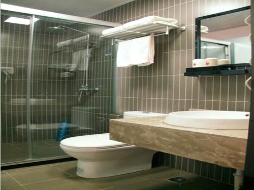 a bathroom with a toilet and a glass shower at Thank Inn Chain Hotel anhui huinan shou county rose residence in Huainan