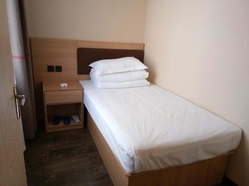 Dormitorio pequeño con cama con sábanas y almohadas blancas en Thank Inn Chain Hotel hebei zhangjiakou xia garden district railway station, en Zhangjiakou