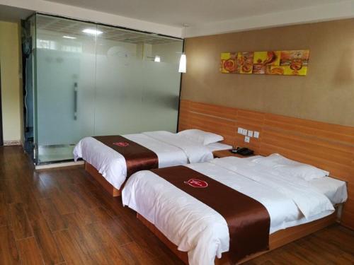 Habitación de hotel con 2 camas y pared de cristal. en Thank Inn Chain Hotel guizhou anshun huangguoshu scenic area, en Anshun