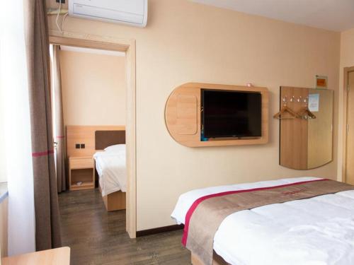 um quarto com uma cama e uma televisão na parede em Thank Inn Chain Hotel hebei zhangjiakou xia garden district railway station em Zhangjiakou