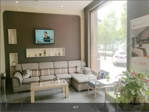 a living room with a couch and tables and a window at Thank Inn Chain Hotel Shanghai jinshan, jinshan new town in Nanhui