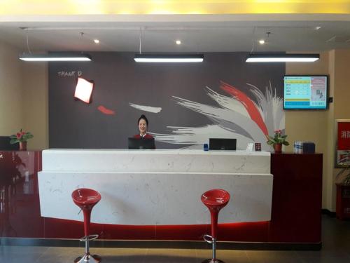 a woman standing behind a counter in a lobby at Thank Inn Chain Hotel Shandong Weifang Changle County Gem City in Weifang