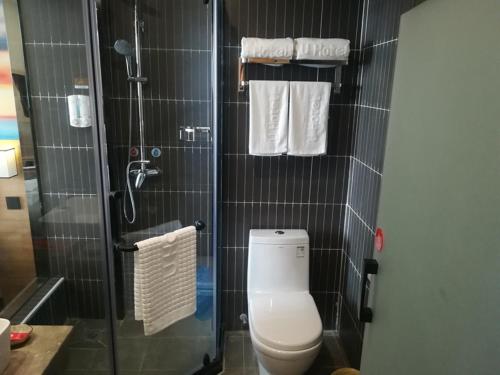 a bathroom with a toilet and a shower with towels at Thank Inn Chain Hotel jiangsu xuzhou jiawang district biantang county in Xuzhou