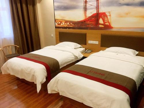 two beds in a hotel room with a painting of a bridge at Thank Inn Chain Hotel shandong zaozhuang central district long-distance bus station in Zaozhuang