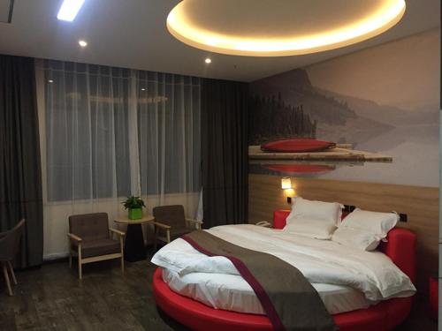 BaoshanにあるThank Inn Chain Hotel Shanghai baoshan district Yang Hang townの大きなベッドと赤い椅子が備わるホテルルームです。