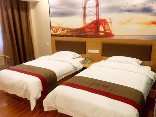 two beds in a hotel room with a painting on the wall at Thank Inn Chain Hotel shandong zaozhuang central district long-distance bus station in Zhaozhuang