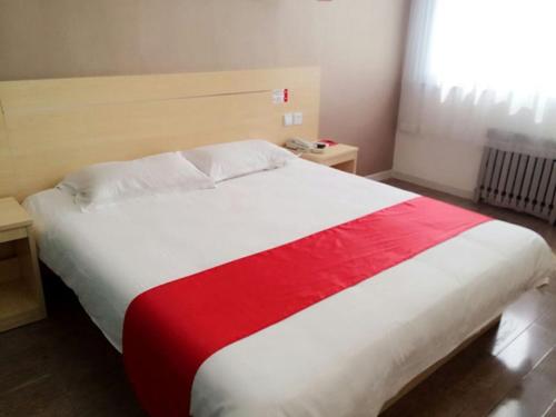 um quarto com uma cama grande e um cobertor vermelho e branco em Thank Inn Chain Hotel shandong yantai high-speed railway sounth station em Yantai
