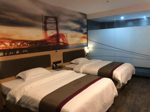 two beds in a hotel room with a painting on the wall at Thank Inn Chain Hotel fujian putian xianyou county lizhong pedestrian street in Putian