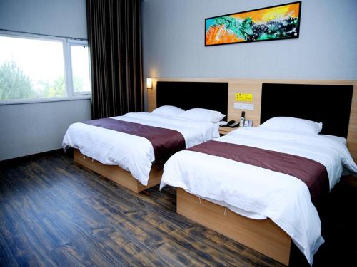 a hotel room with two beds and a tv on the wall at Thank Inn Chain Hotel henan luoyang high-tech district jiudu west road zhoushan station in Luoyang