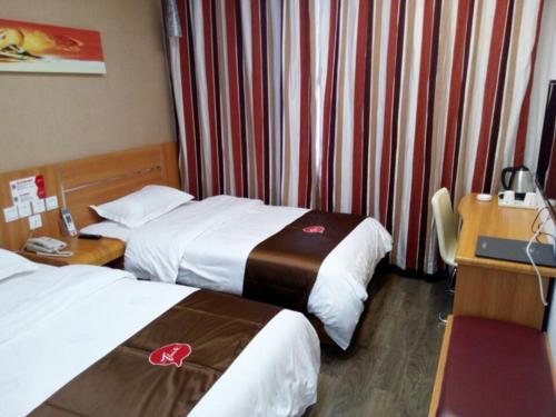 イ坊市にあるThank Inn Chain Hotel shandong weifang fangzi district beihai roadのベッド2台とデスクが備わるホテルルームです。