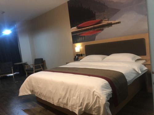a bedroom with a large bed and a painting on the wall at Thank Inn Chain Hotel fujian putian xianyou county lizhong pedestrian street in Putian