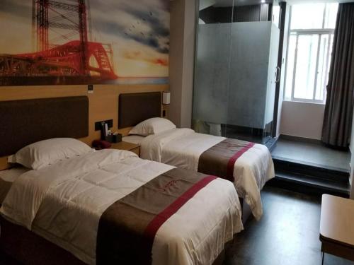 pokój hotelowy z 2 łóżkami i obrazem na ścianie w obiekcie Thank Inn Chain Hotel jiangxi ganzhou zhanggong district civilization avenue w mieście Ganzhou