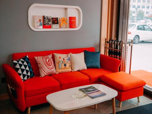 a living room with a red couch and a table at Thank Inn Chain Hotel Jiangsu yancheng pavilion lakes open road in Yancheng