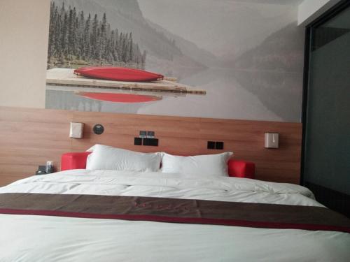 a bedroom with a large bed with a painting on the wall at Thank Inn Chain Hotel Shandong zaozhuang central district ginza mall in Zaozhuang