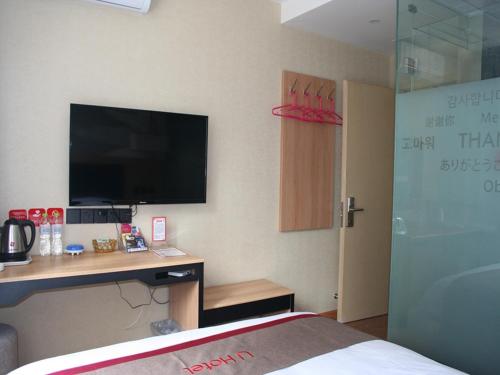 a hotel room with a desk with a television and a bed at Thank Inn Chain Hotel shandong dezhou development zone dongzi cultural park in Dezhou