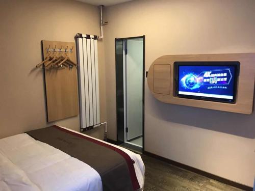 um quarto com uma cama e uma televisão na parede em Thank Inn Chain Hotel gansu lanzhou chengguan district oriental red square em Lanzhou