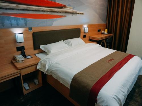 1 dormitorio con 1 cama y escritorio con teléfono en Thank Inn Chain Hotel Jiangsu yancheng pavilion lakes open road, en Yancheng