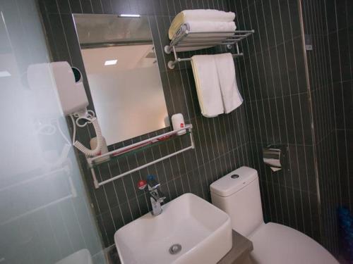 a bathroom with a toilet and a sink and a mirror at Thank Inn Chain Hotel Shanxi linfen YaoDou zone pingyang north street in Linfen