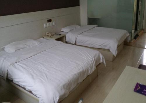2 camas con sábanas blancas en una habitación de hotel en Thank Inn Chain Hotel Shandong Qingdao huangdao chongming island road, en Qingdao