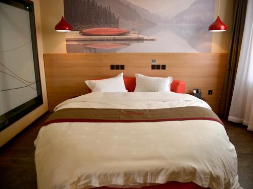 een slaapkamer met een groot wit bed en een schilderij aan de muur bij Thank Inn Chain Hotel Jiangsu xuzhou gulou DaHuangShan in Xuzhou