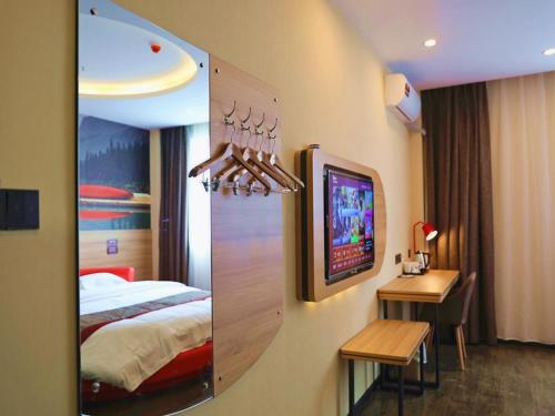 a hotel room with a bed and a desk and a television at Thank Inn Chain Hotel Jiangsu Yancheng dongtai Jianggang town in Cuiguangshan