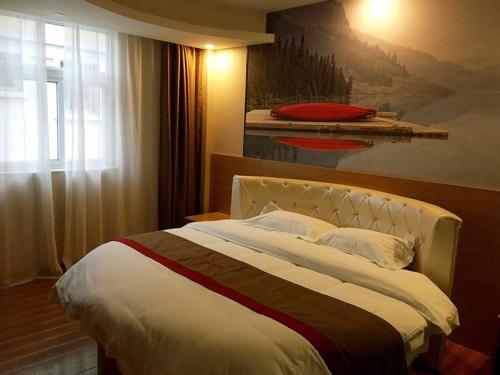 a bedroom with a large bed with a painting on the wall at Thank Inn Chain Hotel shandong zaozhuang central district long-distance bus station in Zhaozhuang