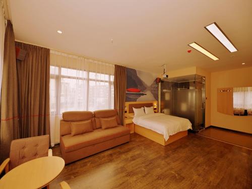 a bedroom with a bed and a couch and a table at Thank Inn Chain Hotel sichuan ziyang yanjiang district walmart in Ziyang