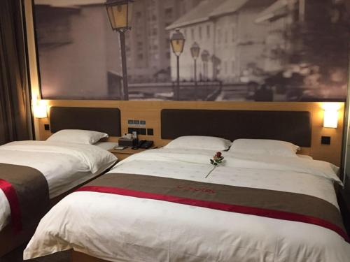 two beds in a hotel room with flowers on them at Thank Inn Chain Hotel guizhou zunyi chishui city red army avenue jinshui bay in Chishui