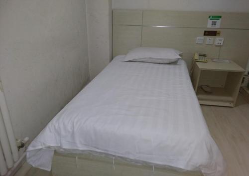 Cama blanca en habitación pequeña con mesa en Thank Inn Chain Hotel Shandong Qingdao huangdao chongming island road, en Qingdao