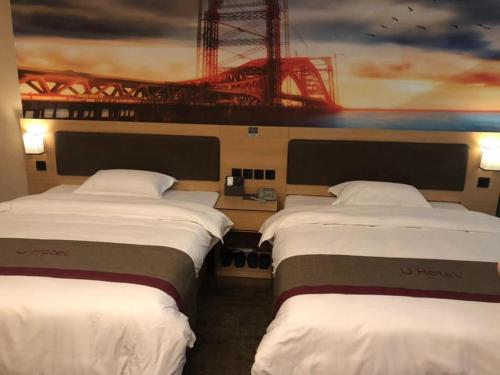 two beds in a room with a painting on the wall at Thank Inn Chain Hotel fujian putian xianyou county lizhong pedestrian street in Putian
