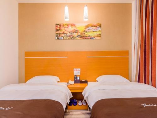 two beds in a hotel room with a desk at Thank Inn Chain Hotel Guangdong Guangzhou Baiyun International Airport in Guangzhou