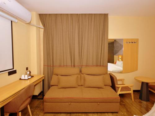 um quarto com um sofá, uma secretária e uma cama em Thank Inn Chain Hotel sichuan ziyang yanjiang district walmart em Ziyang
