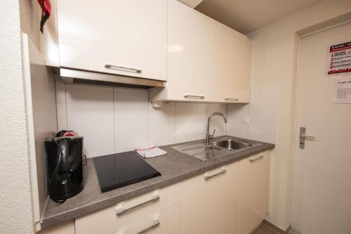 a small kitchen with white cabinets and a sink at Haus Astoria in Saas-Grund
